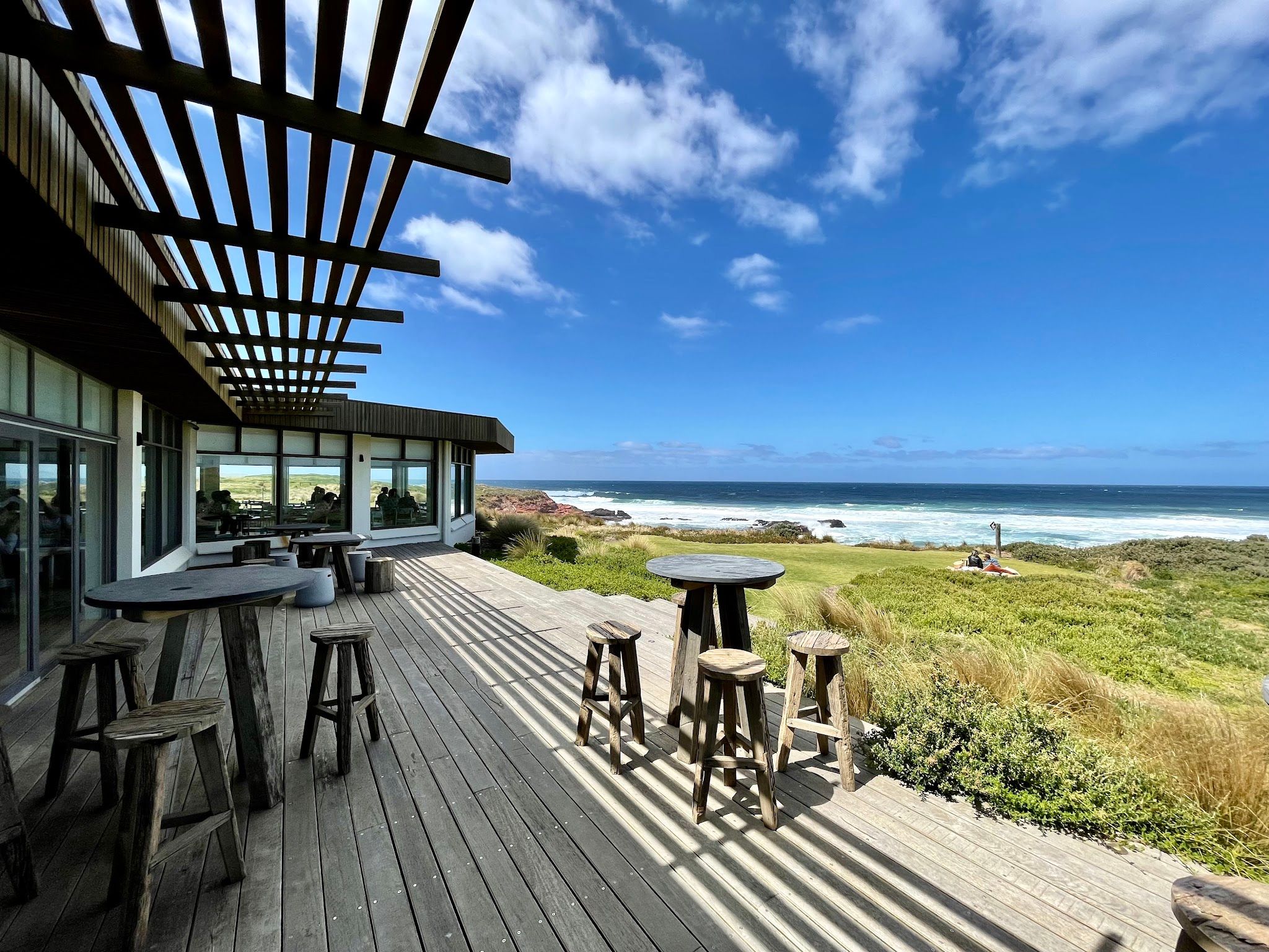 The Cape Kitchen outdoor deck terrace with ocean views, timber bar tables and blue sky