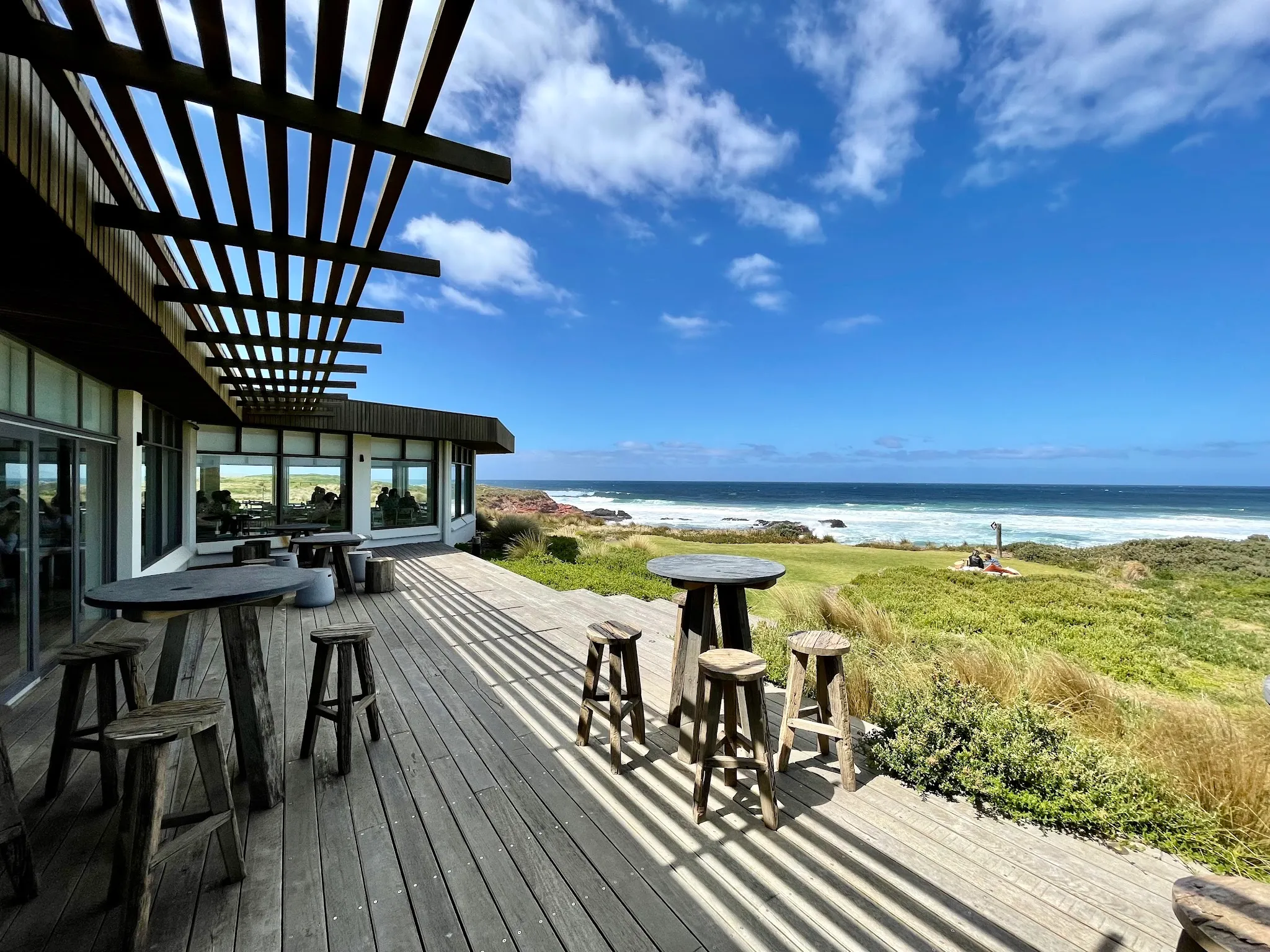 The Cape Kitchen outdoor deck terrace with ocean views, timber bar tables and blue sky