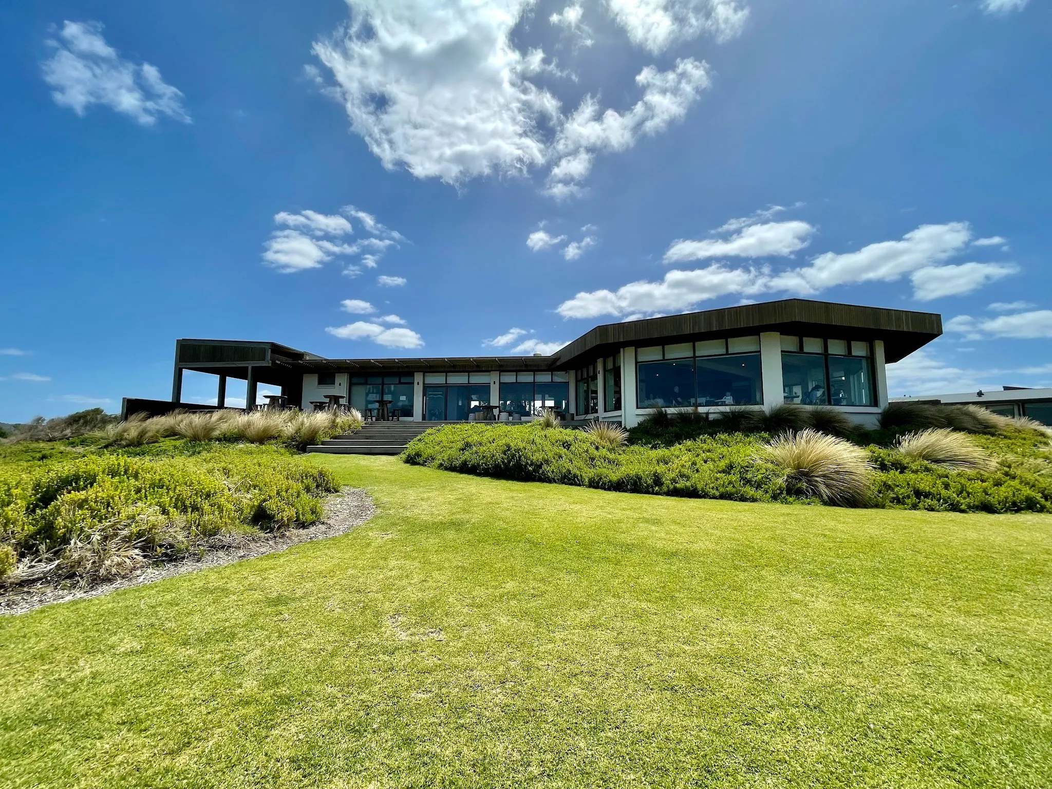 The Cape Kitchen building exterior on a sunny day, surrounded by green lawns and coastal landscaping