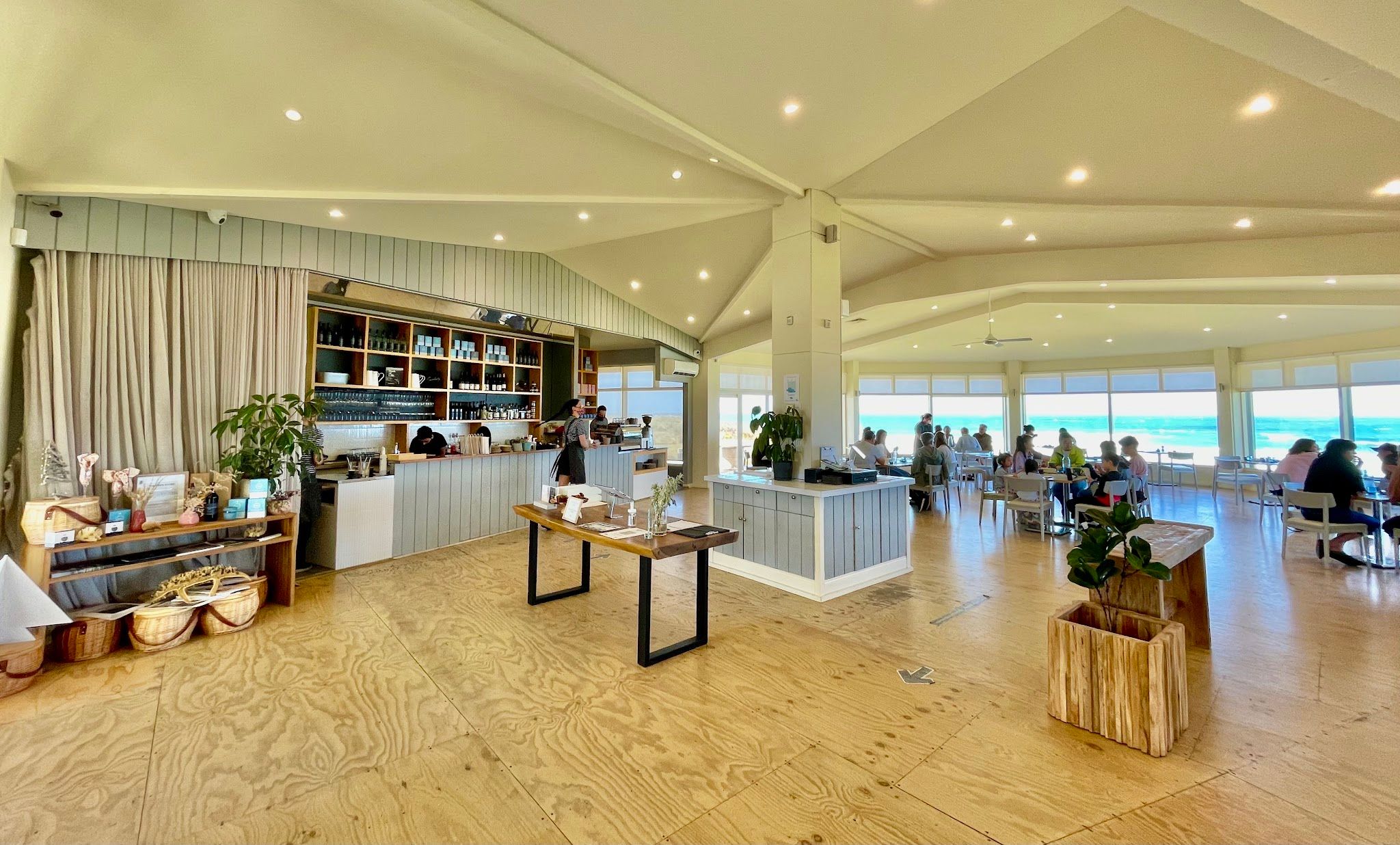 The Cape Kitchen full dining room and bar, busy with diners in front of panoramic ocean windows