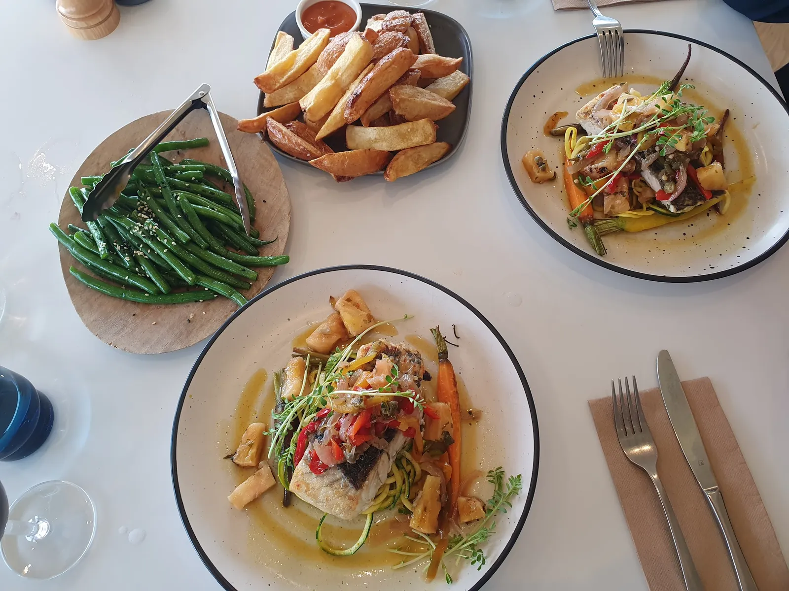 Table spread of baked fish, thick-cut chips and stir-fried vegetables at The Cape Kitchen